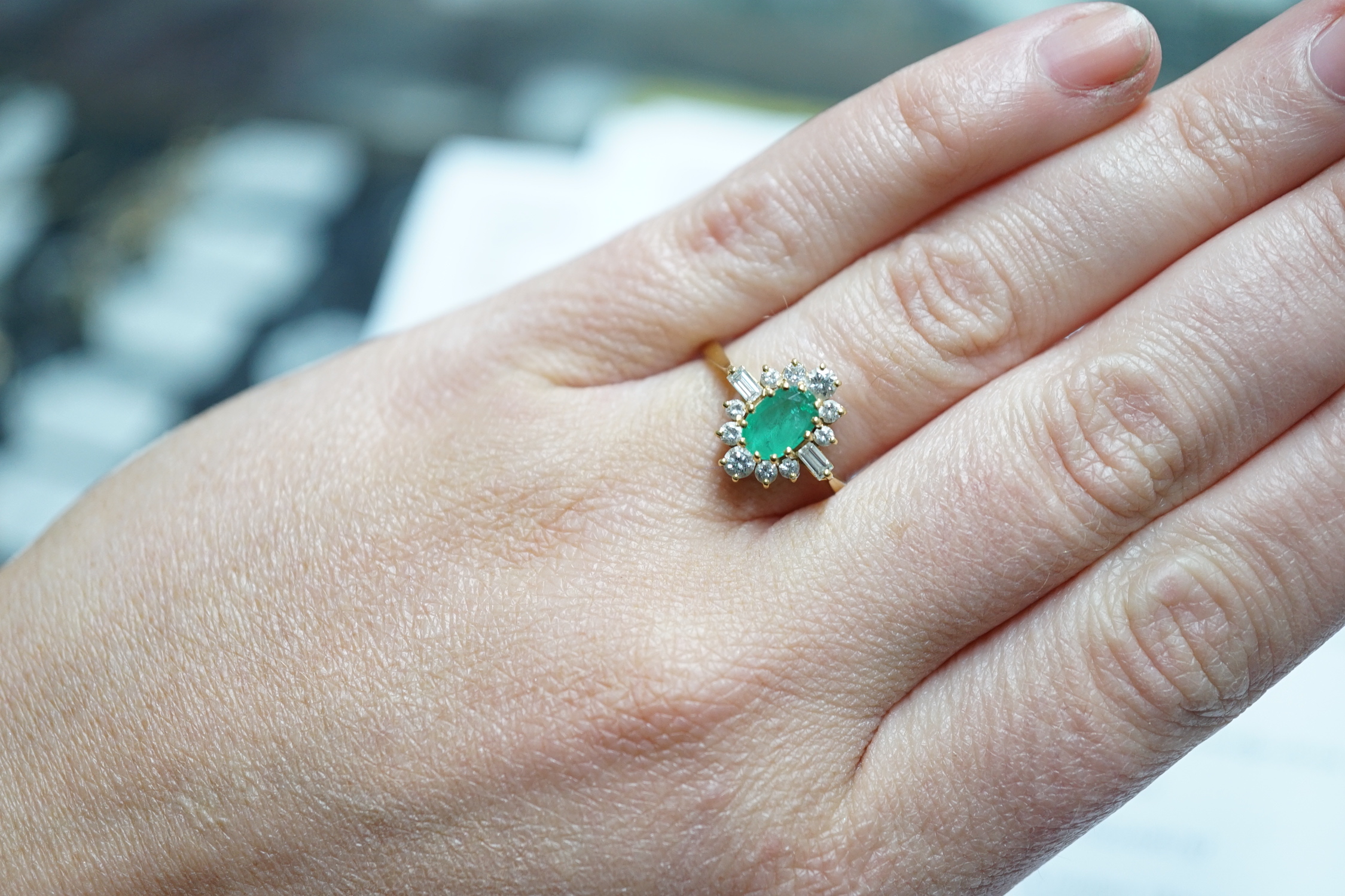 A modern 18ct gold, single stone oval cut emerald and round and baguette cut diamond cluster set ring, size P/Q, size 3 grams.
